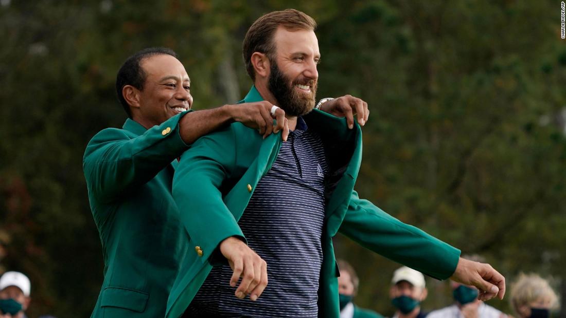 Tiger Woods helps Masters&#39; champion Dustin Johnson with his green jacket after his victory at the Masters golf tournament Sunday, Nov. 15, 2020, in Augusta, Ga. 
