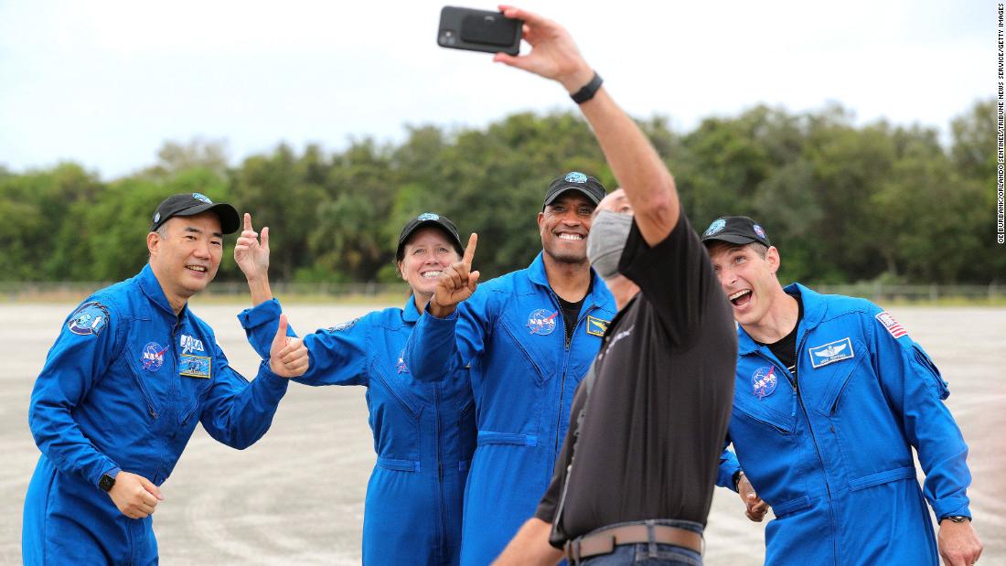 The crew of the SpaceX Crew-1 mission pose for a photo with a SpaceX employee on November 8 at Kennedy Space Center.