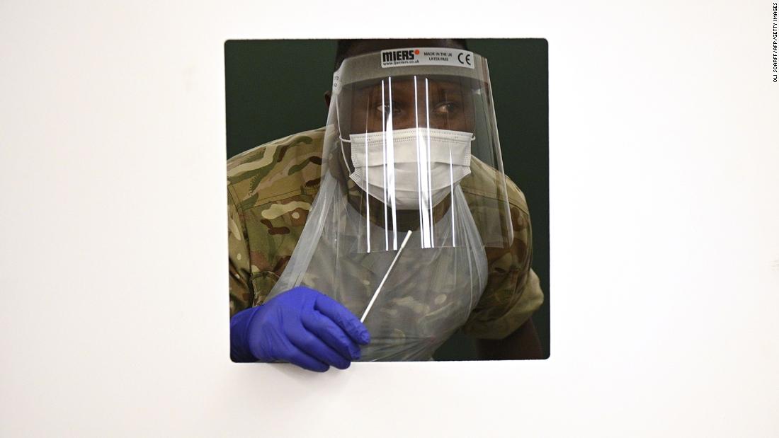 A soldier waits at a window for a colleague&#39;s swab as they practice inside a rapid testing center in Liverpool, England, on November 6.