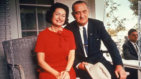 President Johnson sits on a porch swing with First Lady Lady Bird following his landslide election win. 