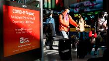 Travelers walk through Newark International Airport on November 21, 2020 in Newark, New Jersey. - Current US numbers -- more than a quarter of a million deaths have been reported -- have alarmed authorities enough to advise that people stay home for the November 26 Thanksgiving holiday, when Americans usually travel to be with their families. (Photo by Kena Betancur / AFP) (Photo by KENA BETANCUR/AFP via Getty Images)