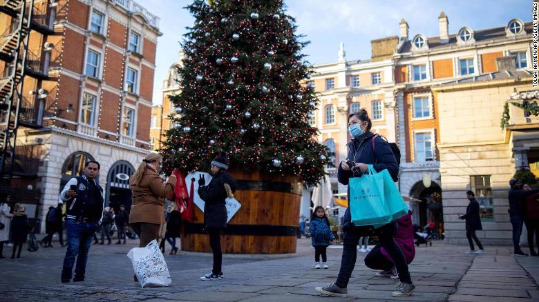 Pedestrians wearing masks pass a Christmas tree in Covent Garden in central London on November 22, during England's four-week national lockdown.