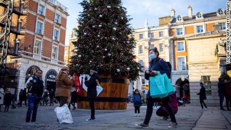 Pedestrians wearing masks pass a Christmas tree in Covent Garden in central London on November 22, during England&#39;s four-week national lockdown.