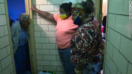 Regina Status, right, and her 13-year-old daughter, middle, provide food to their elderly neighbor Mammie Vinning in the Bronx.