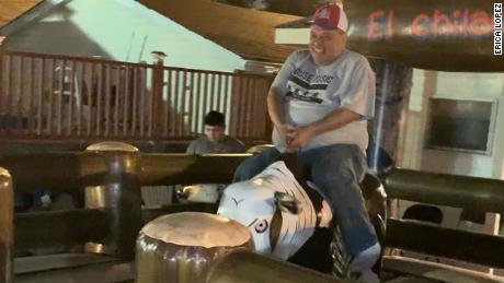 Lopez rides a mechanical bull.