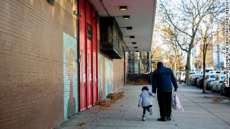 A parent walks their child to school in New York, Nov. 16, 2020. After announcing school closures on Nov. 18, New York City Mayor Bill de Blasio said this week some schools will begin moving toward in-person classes again 