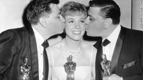 Richard Sherman (left) and Robert Sherman (right) with Julie Andrews (center) hold their Oscar statues in 1965 for their work on the film Mary Poppins.