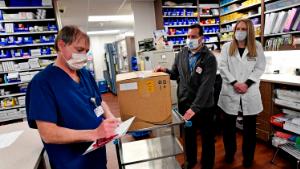 Vail Health Hospital pharmacy technician Rob Brown, left, signs the necessary paperwork to take possession of mock Covid-19 vaccines from courier driver Leo Gomez, center, as pharmacist Jessica Peterson watches over the process in the pharmacy on December 8, 2020 in Vail, Colorado.  With the state expecting its first shipment of a COVID-19 vaccine in a matter of days, the state health department ran an exercise to see how ready it is to take on such a mass vaccination campaign. The Pfizer vaccine, which is the first shot expected to gain federal approval, will be difficult for the state to distribute as it needs to be stored at sub-zero temperatures and requires two shots. The Colorado Division of Homeland Security and Emergency Management held a dry run or drill of receiving the vaccines in a thermal shipping container at Denver International Airport, using a courier car to take the vaccines to Vail Health Hospital and then the path the vaccines will follow once at the hospital from the pharmacy to a patient receiving the vaccine. (Photo by Helen H. Richardson/MediaNews Group/The Denver Post via Getty Images)