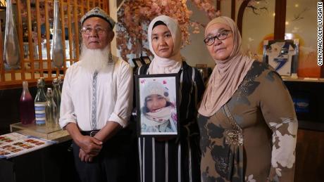 Marhaba Yakub Salay (centre) holds a framed photograph of her sister, Mayila Yakufu, who was sent sent to detention centre in Xinjiang. 