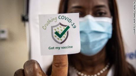 A nurse who was one of the first people in the US to get the Covid-19 vaccine holds up a vaccination sticker.