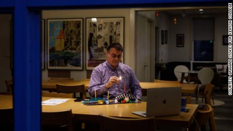 Through the window of Rothenberg Hillel House at Kenyon College in Ohio, Jewish Chaplain Marc Bragin can be seen lighting a candle over Zoom to mark the first night of Hanukkah.