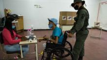 A soldier helps a man on a wheelchair as he votes at a polling station in a school in Caracas, on December 6.