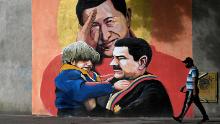 A mural depicting Venezuelan late President Hugo Chavez (C) saluting and Venezuelan President Nicolas Maduro (R) holding a child in Caracas on December 9, 2020. 