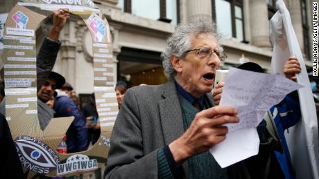 Piers Corbyn speaks to demonstrators as a man holds up a QAnon sign behind him during a StandUpX protest in London this October.