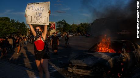 A protester hold sign board &quot;Justice for George&quot; into a fire outside a Target store near the Third Police Precinct on May 28, 2020 in Minneapolis, Minnesota, during a demonstration over the death of George Floyd.