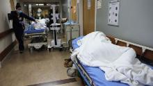 APPLE VALLEY, CALIFORNIA - DECEMBER 23:  (EDITORIAL USE ONLY) A patient lies on a stretcher in the hallway of the overloaded Emergency Room at Providence St. Mary Medical Center amid a surge in COVID-19 patients in Southern California on December 23, 2020 in Apple Valley, California. The 213 bed capacity hospital in San Bernardino County is currently treating at least 140 COVID 19-positive inpatients while operating at approximately 250 percent of ICU capacity. Southern California remains at zero percent of its ICU (Intensive Care Unit) bed capacity amid the spike in coronavirus cases and hospitalizations. (Photo by Mario Tama/Getty Images)