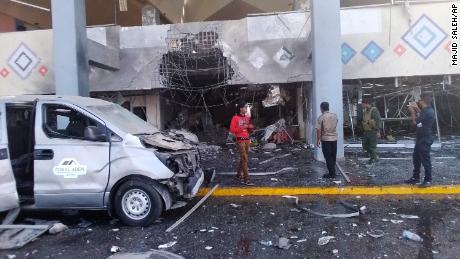 Bystanders and a soldier stand near a damaged portion of the airport of Yemen&#39;s southern city of Aden&#39;s after an explosion, Wednesday, Dec. 30, 2020. The blast struck the airport building shortly after a plane carrying the newly formed Cabinet landed on Wednesday. No one on the government plane was hurt.  (AP Photo/Majid Saleh)