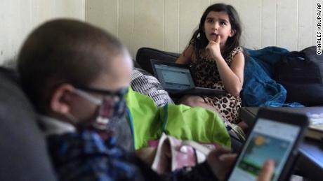 Third grader Elena recites multiplication tables as her brother Wyatt reviews his kindergarten work on a tablet with their mom, Christi Brouder, in Haverhill, Massachusetts. 