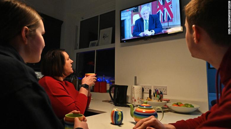 A family gather around the television in Liverpool, northwest England to watch Boris Johnson give a televised message to the nation on January 4, 2021.