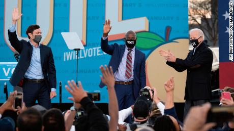 Democratic candidates for Senate Jon Ossoff (L), Raphael Warnock (C) and US President-elect Joe Biden (R) stand on stage during a rally outside Center Parc Stadium in Atlanta, Georgia, on January 4, 2021.