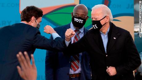 Democrats Jon Ossoff (left), Raphael Warnock (center) and President-elect Joe Biden slammed elbows on stage during a rally in Atlanta on January 4, 2021.