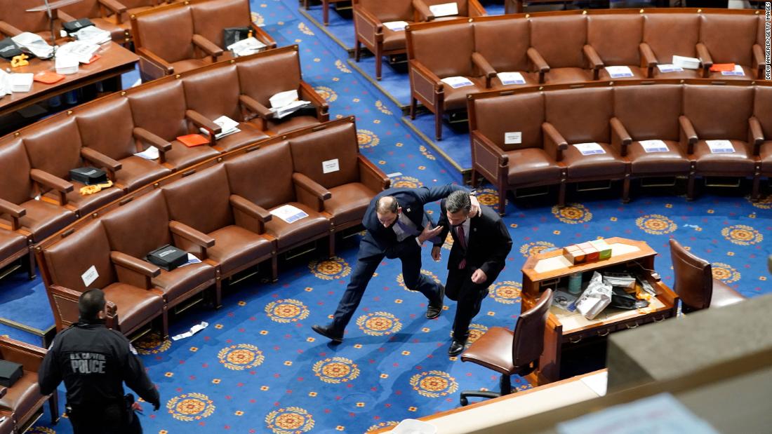 Members of Congress run for cover as rioters try to enter the House chamber.