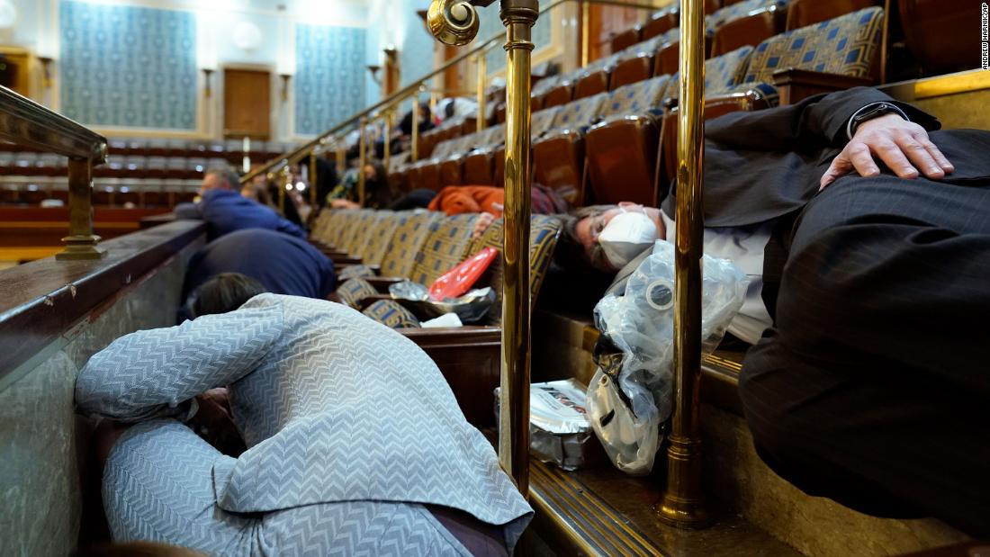 People take shelter in the House chamber as rioters try to break in. House members were given gas masks that were under the seats, according to a pool reporter on the House floor.