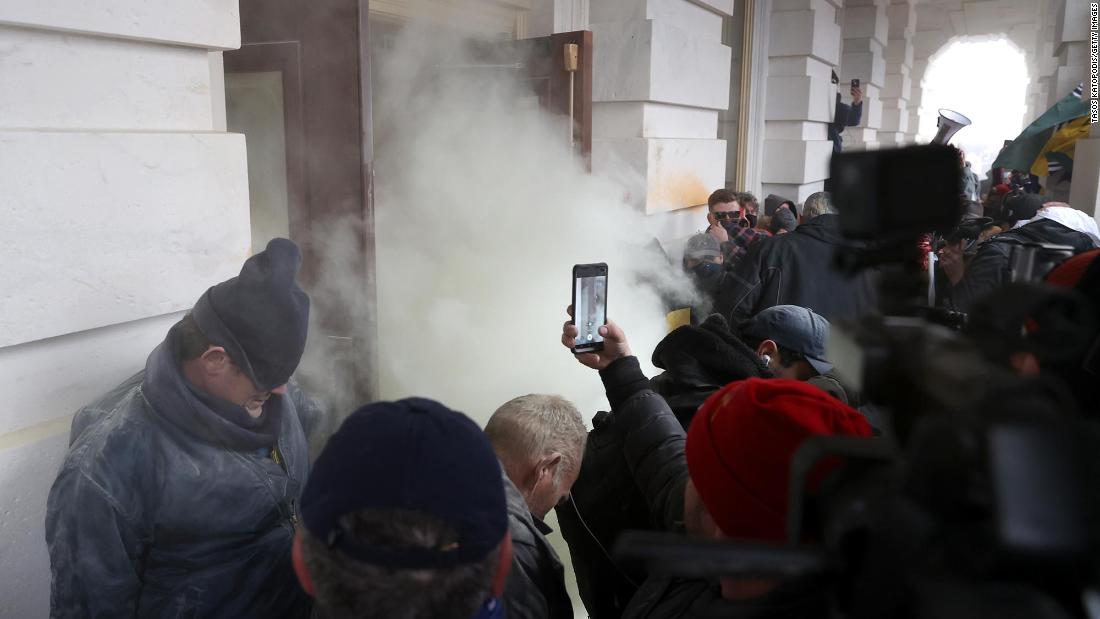 Tear gas is deployed as rioters gather outside the Capitol.