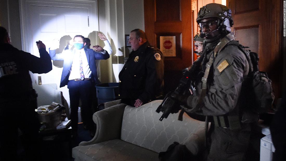 Congressional staffers hold up their hands while Capitol Police SWAT teams secure the US Capitol.