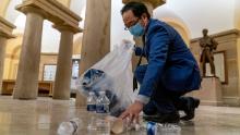 Rep. Andy Kim, D-N.J., cleans up debris and trash strewn across the floor in the early morning hours of Thursday, Jan. 7, 2021, after protesters stormed the Capitol in Washington, on Wednesday. (AP Photo/Andrew Harnik)