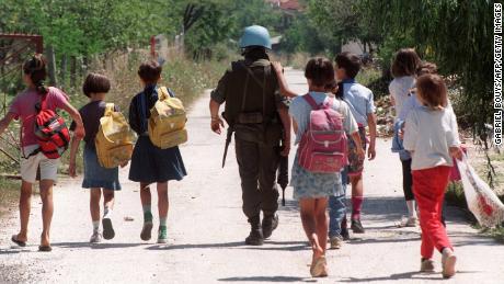 A United Nations Protection Force French soldier escorts a group of children after they left their school in a Sarajevo neighborhood a few hundred meters from the front line on August 14, 1993.