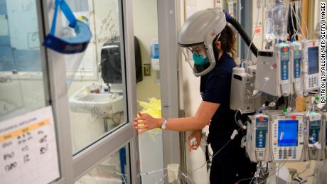 A nurse wearing personal protective equipment (PPE), including a personal air purifying respirator (PAPR), closes a door to a patient&#39;s room in a Covid-19 intensive care unit at Martin Luther King Jr. (MLK) Community Hospital on January 6, in the Willowbrook neighborhood of Los Angeles.