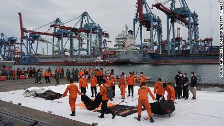 Search and rescue team members carry bags containing remains of victims recovered from the Sriwijaya Air SJ 182 crash site on the dockside at Tanjung Priok Port in Jakarta, Indonesia, on Sunday.