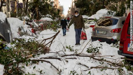 People walk along a road with fallen branches a day after the heaviest snowfall in decades on January 10 in Madrid, Spain. 