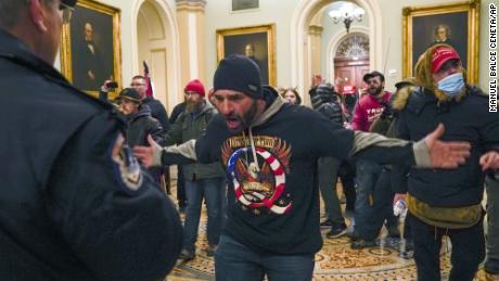 Trump supporters gesture to U.S. Capitol Police in the hallway outside of the Senate chamber at the Capitol in Washington, Wednesday, Jan. 6, 2021. (AP Photo/Manuel Balce Ceneta)