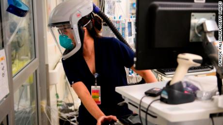 A nurse wearing personal protective equipment (PPE) including a personal air purifying respirator (PAPR) looks through a door into a patients room in a Covid-19 intensive care unit (ICU) at Martin Luther King Jr. (MLK) Community Hospital on January 6, 2021 in the Willowbrook neighborhood of Los Angeles, California. - Deep within a South Los Angeles hospital, a row of elderly Hispanic men in induced comas lay hooked up to ventilators, while nurses clad in spacesuit-looking respirators checked their bleeping monitors in the eerie silence. The intensive care unit in one of the city&#39;s poorest districts is well accustomed to death, but with Los Angeles now at the heart of the United States&#39; Covid pandemic, medics say they have never seen anything on this scale. (Photo by Patrick Fallon/AFP/Getty Images)