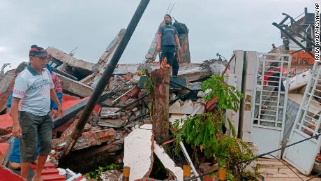 Warga memeriksa rumah yang rusak akibat gempa di Mamuju, Sulawesi Barat, Indonesia pada hari Jumat.