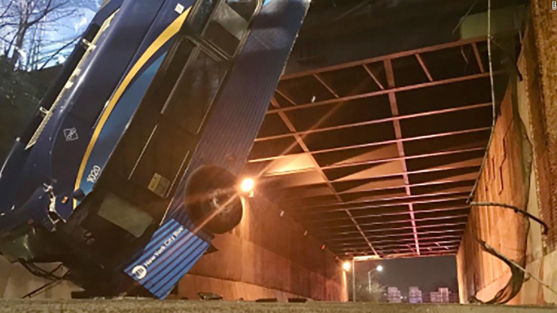 The New York bus hangs out of the road following an accident in which at least seven people were injured