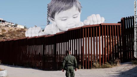 A US Border Patrol officer stands near artwork installed on the Mexican side of the border near Tecate, California.