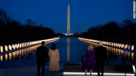 With the Washington Monument in the background, President-elect Joe Biden with his wife Jill Biden and Vice President-elect Kamala Harris with her husband Doug Emhoff listen as Yolanda Adams sings &quot;Hallelujah&quot; during a COVID-19 memorial, with lights placed around the Lincoln Memorial Reflecting Pool, Tuesday, Jan. 19, 2021, in Washington. (AP Photo/Evan Vucci)