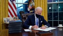 President Joe Biden signs his first executive order in the Oval Office of the White House on Wednesday, Jan. 20, 2021, in Washington. (AP Photo/Evan Vucci)