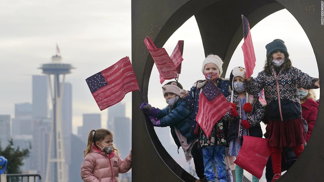 Members of the Children&#39;s Workshop, an arts and science preschool in Seattle, pause in a sculpture while walking with flags they made to celebrate the inauguration.