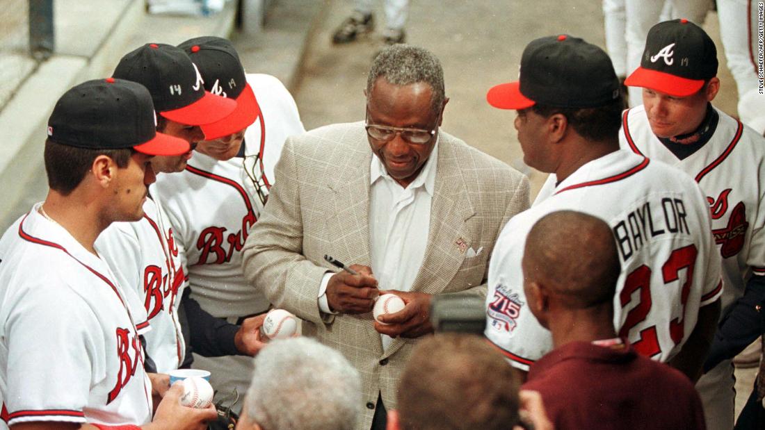 Aaron signs autographs for some of the Atlanta Braves in 1999.