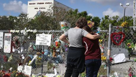 Margarita Lasalle (right) and Joellen Berman look on at the memorial in front of Marjory Stoneman Douglas High School as faculty and staff return to the school for the first time since the mass shooting on February 23, 2018.