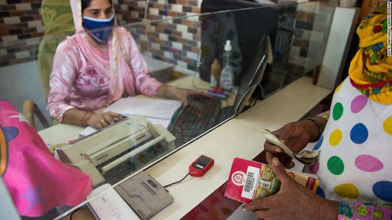 A business correspondent agent helps a woman with a bank transaction in Silana, India.