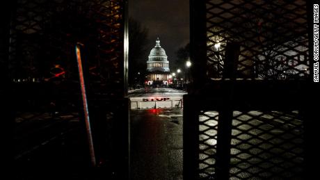Snow falls as the U.S. Capitol building is seen past a perimeter fence on January 25, 2021 in Washington, DC.