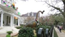 Passersby look at dinosaur figures at a mansion on St.  Charles avenue.
