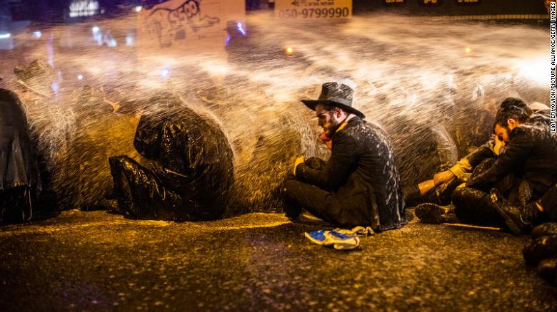 Israeli policemen use water cannon to disperse an anti-lockdown demonstration staged in Bnei Brak by ultra-Orthodox Jews on December 27.