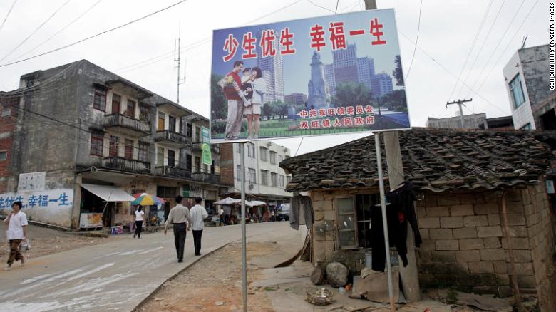 Афиша политики одного ребенка, гласящая: "имейте меньше детей, имейте лучшую жизнь", приветствует жителей на главной улице Шуанвана на юге Китая в 2007 году.