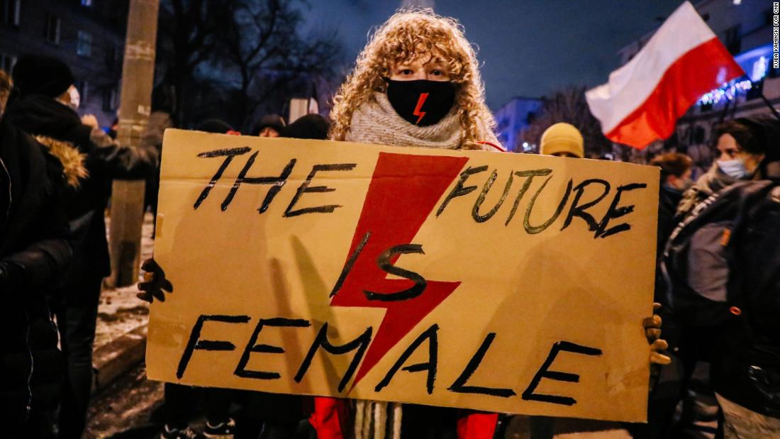 Weronika, 22, holds a banner with the Women's Strike symbol.
